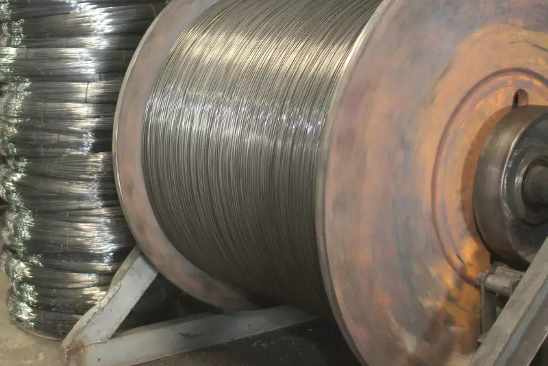 Carrete de alambre junto a rollos apilados en la planta